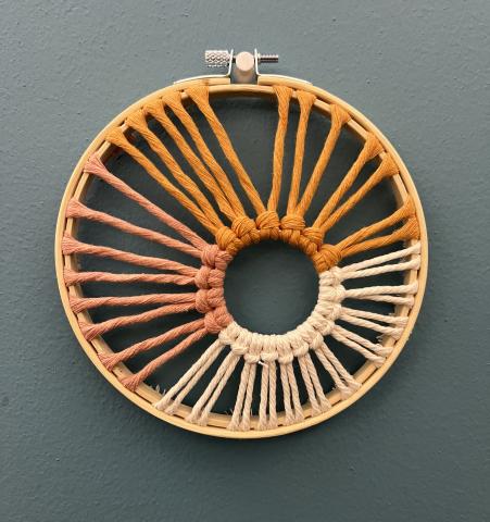 sunburst made from macrame in an embroidery hoop on a blue background