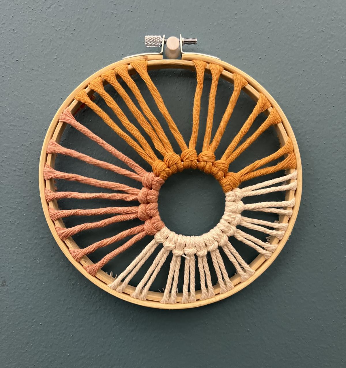 sunburst made from macrame in an embroidery hoop on a blue background